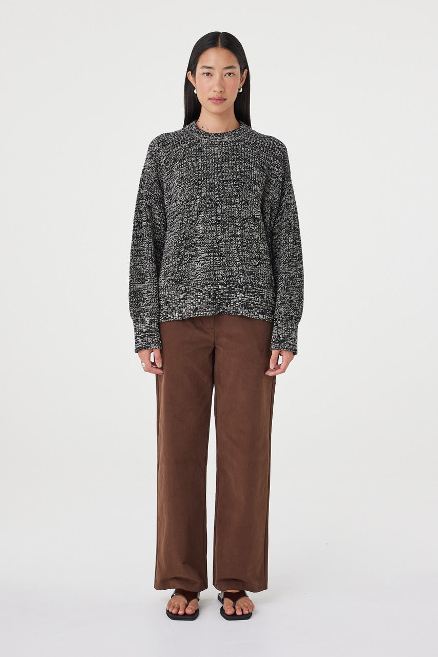 Full-length front view of the Solene Sweater in black and taupe featuring a chunky marled knit texture, oversized silhouette and ribbed hem styled with espresso pants