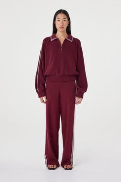 Front close-up view of the Nella Zip in merlot and cream featuring contrast piping along the collar and sleeves, a silver 1/4 zip closure and ribbed waistband detail styled with matching knit pants
