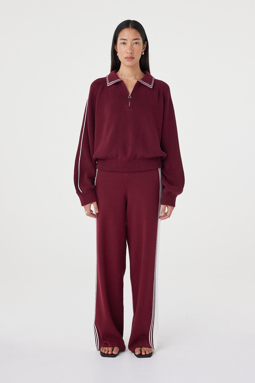 Front close-up view of the Nella Zip in merlot and cream featuring contrast piping along the collar and sleeves, a silver 1/4 zip closure and ribbed waistband detail styled with matching knit pants
