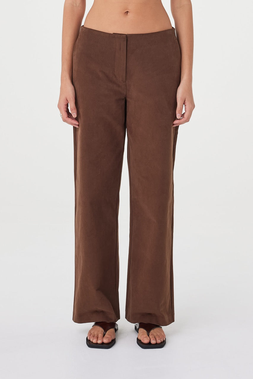 Close-up front view of the Avery Pant in espresso showcasing the velvet finish, minimal waist detailing and relaxed straight-leg fit, styled with dark brown sandals