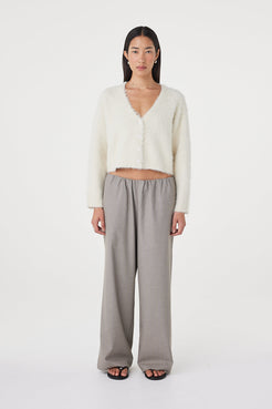 Full-length front view of the Liora Fluffy Cardigan in cream styled with relaxed taupe pants, featuring a button-up front, deep neckline and easy oversized drape
