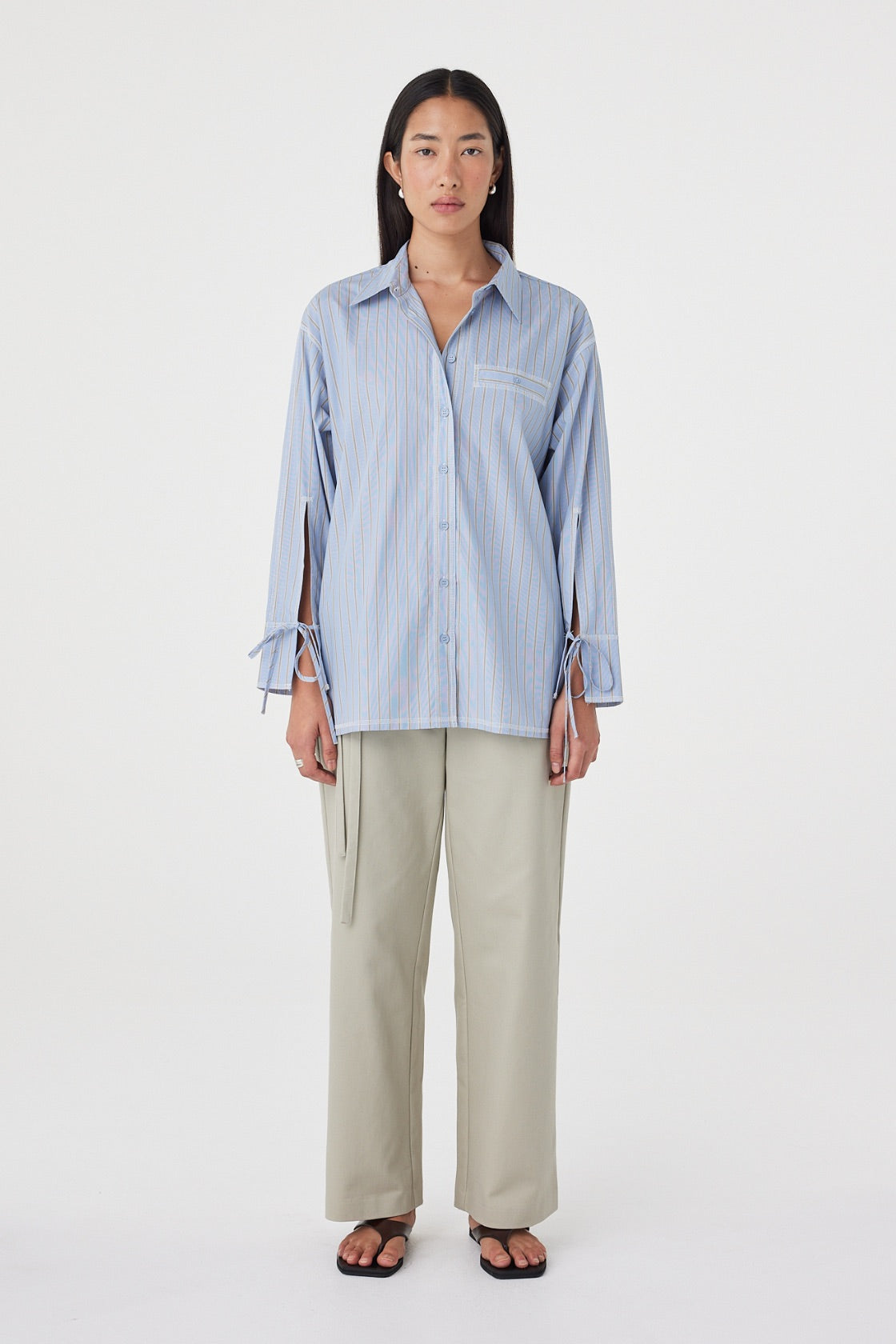 Full-length front view of the Blair Shirt in Blue Taupe Stripe highlighting the relaxed silhouette, oversized cuffs with tie detail and contrast overlocking.