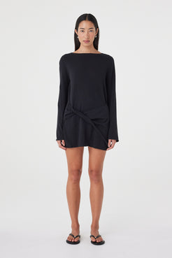 Front view of the Kira Mini Dress in Black featuring a boat neckline, long sleeves and twisted wrap detail through the front.
