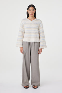 Front view of the Lucca Sweater in taupe and blue stripe featuring a soft fluffy knit texture, relaxed cropped silhouette and deep V-neckline styled with relaxed taupe pants and black sandals