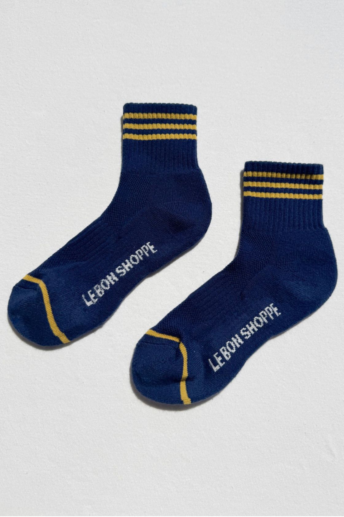 Pair of navy socks with yellow stripe detail and contrast trim laid flat