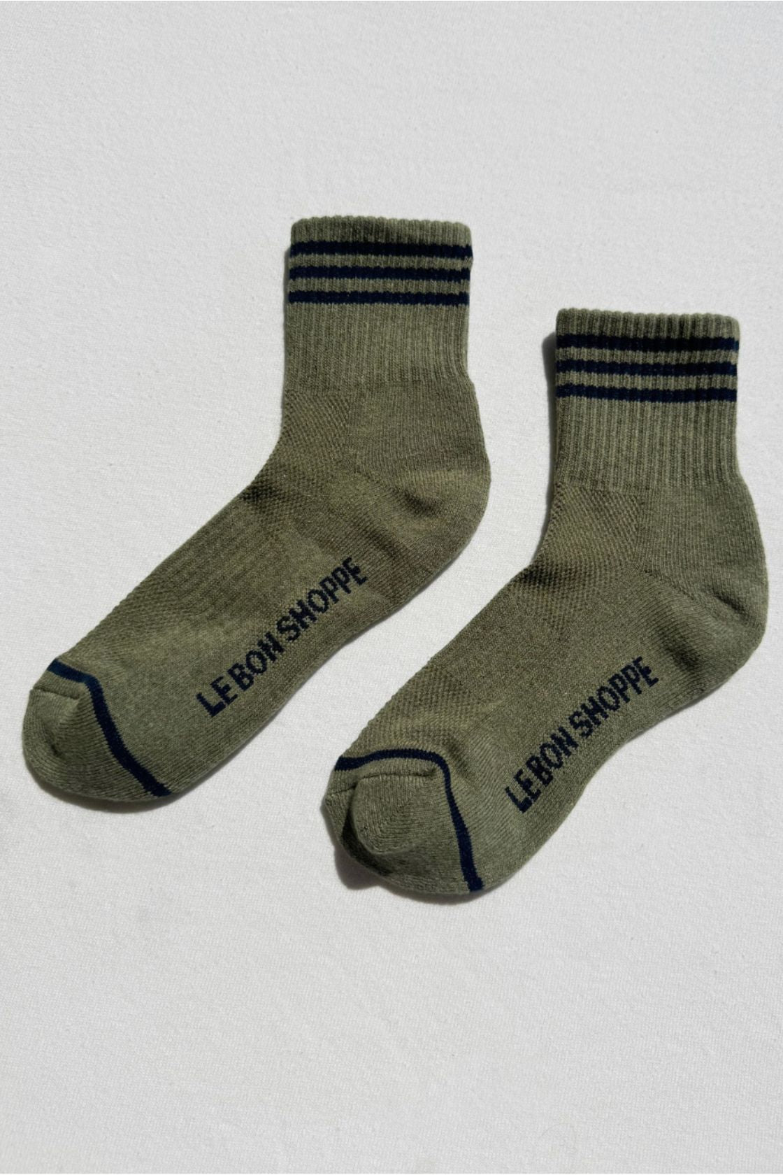 Pair of sage green socks with dark stripe detail and contrast trim laid flat