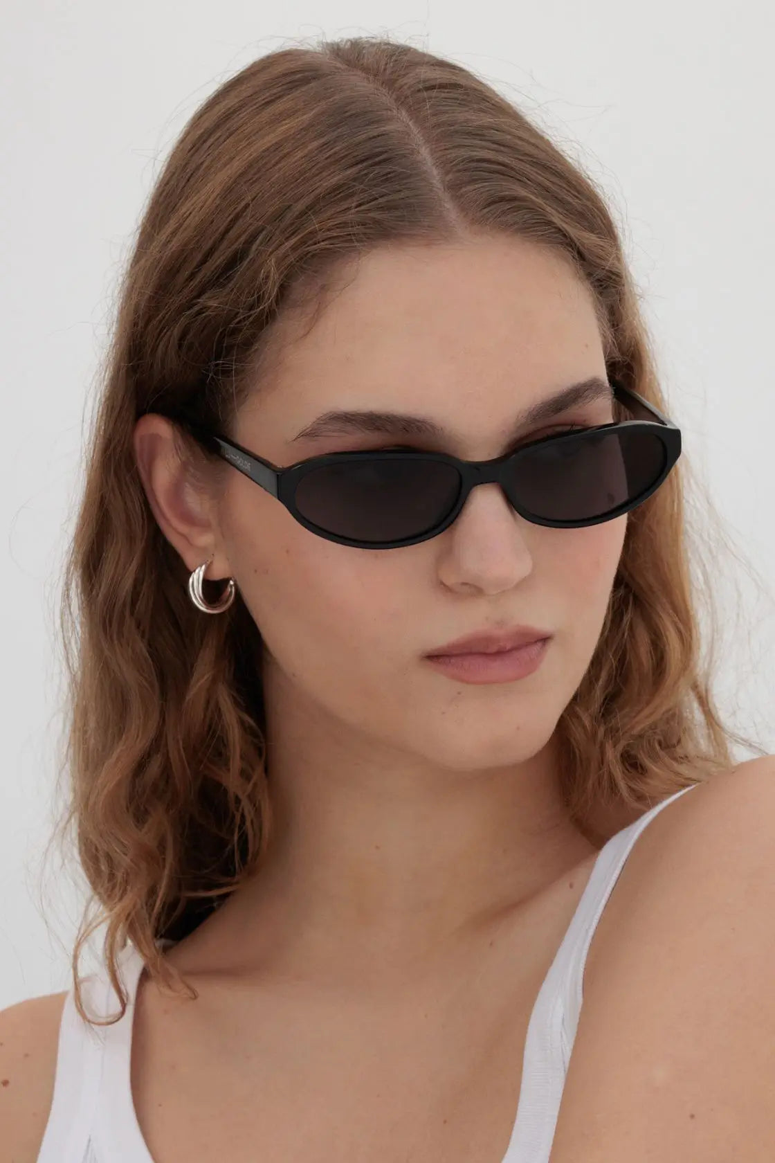 Side profile of model wearing sculptural black sunglasses, blending statement design with easy everyday wear.