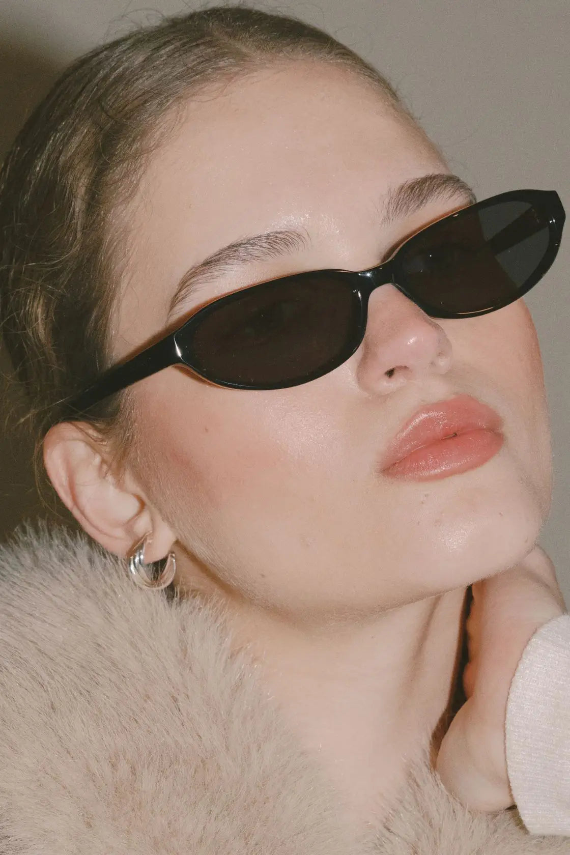 Model in faux fur jacket wearing glossy black sunglasses, capturing a retro-luxe moment in transitional season layering.