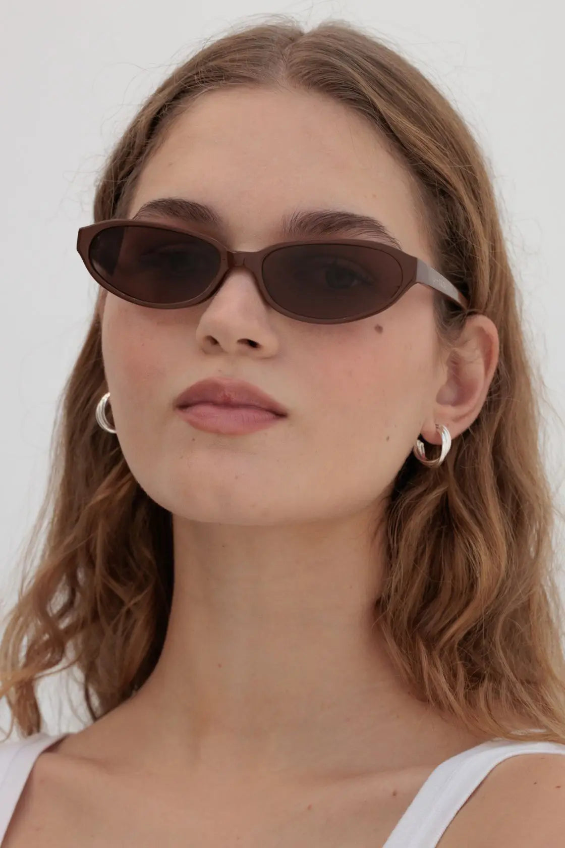 Side profile of cinnamon sunglasses worn with clean makeup and white tank, ideal for late summer to early autumn transitions.