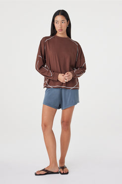 Full-length front view of the Kesh LS Tee in Espresso & Cream showcasing the relaxed fit, long sleeves and contrast stitching, paired with blue lounge shorts.
