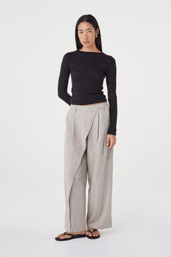Full-length view of the Aston LS in Black showcasing the slim fit, long sleeves and soft drape through the body, paired with taupe wide-leg trousers and sandals.
