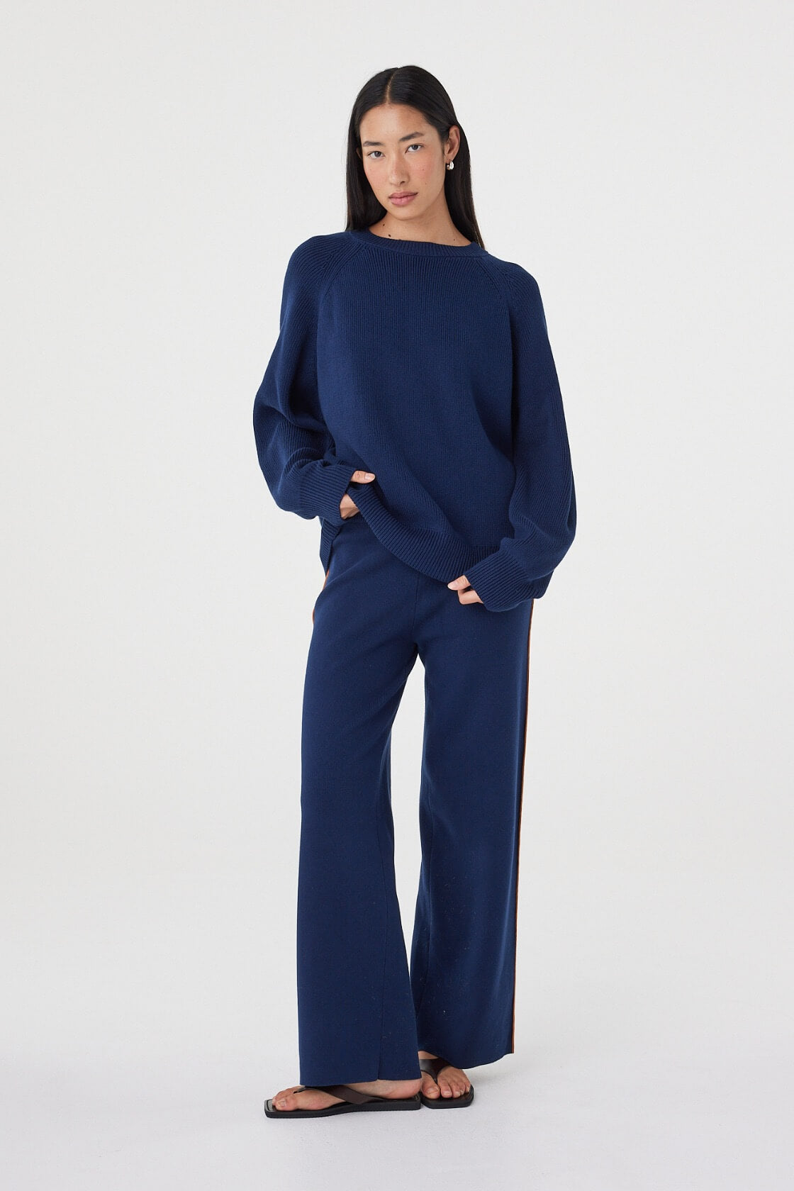 Full-length view of the Aubrey Sweater in Navy showcasing the relaxed fit, ribbed hem and cuffs, paired with coordinating navy knit pants and sandals.
