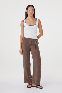 Full-length front view of the Kaya Tank in Cream & Teal showcasing the fitted silhouette and contrast neckline and straps, paired with relaxed brown pants.