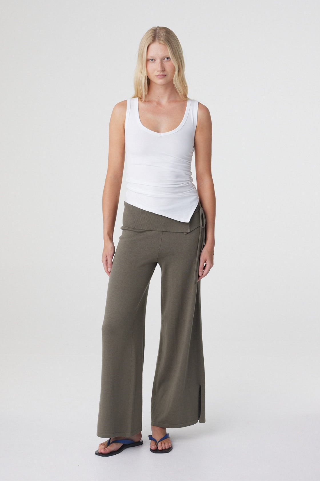 Nora Pant in Smokey Olive, full length front view styled with a white tank, showing the relaxed wide leg shape and asymmetric waist detail.