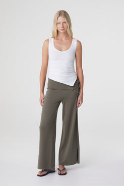 Nora Pant in Smokey Olive, full length front view styled with a white tank, showing the relaxed wide leg shape and asymmetric waist detail.