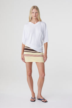 Blaine Tee in White, full front view styled with the Mara Mini Skirt, showing the relaxed shape and asymmetric hemline.