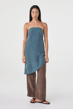 Full-length front view of the Rhea Dress in Teal layered over espresso pants, showing the fluid drape and asymmetrical silhouette.