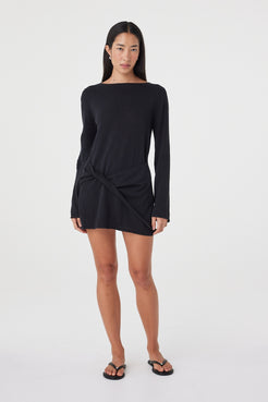 Full-length front view of the Kira Mini Dress in Black showcasing the mini silhouette, long sleeves and softly gathered twist detail, styled with black sandals.