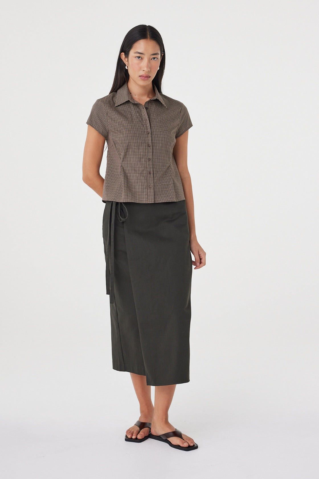 Full-length front view of the Freya Shirt in Chocolate Check showcasing the tailored fit, princess seam detailing and cap sleeves, paired with a charcoal midi skirt and sandals