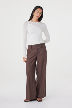 Angled front view of the Manon Pant in Espresso Pinstripe styled with a fitted white top, highlighting the tailored waist and effortless drape.