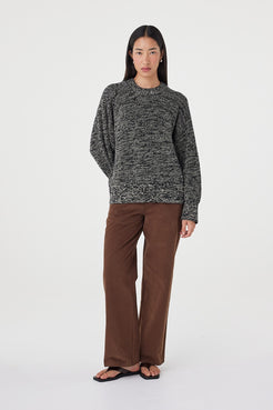 Angled full-length view of the Solene Sweater in black and taupe styled with espresso tailored pants and black sandals for an elevated everyday look