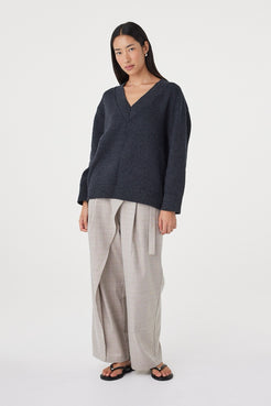 Angled view of the Zenya Sweater in Dark Grey Marle showing the deep V-neckline, soft knit texture and effortless drape through the body.