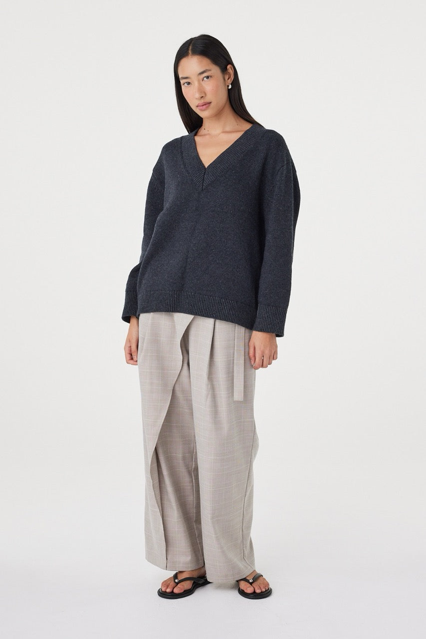 Angled view of the Zenya Sweater in Dark Grey Marle showing the deep V-neckline, soft knit texture and effortless drape through the body.