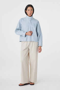 Three-quarter front view of the Addie Jacket in Pale Blue highlighting the relaxed silhouette, adjustable toggle hem and lightweight cotton fabrication.