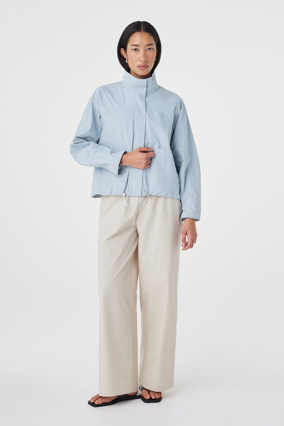 Three-quarter front view of the Addie Jacket in Pale Blue highlighting the relaxed silhouette, adjustable toggle hem and lightweight cotton fabrication.