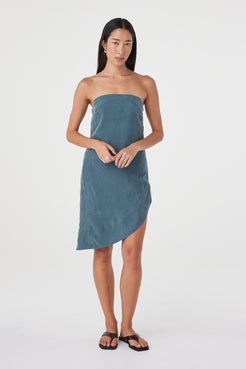 Front styled view of the Rhea Dress in Teal worn on its own, showing the soft drape and asymmetrical length.