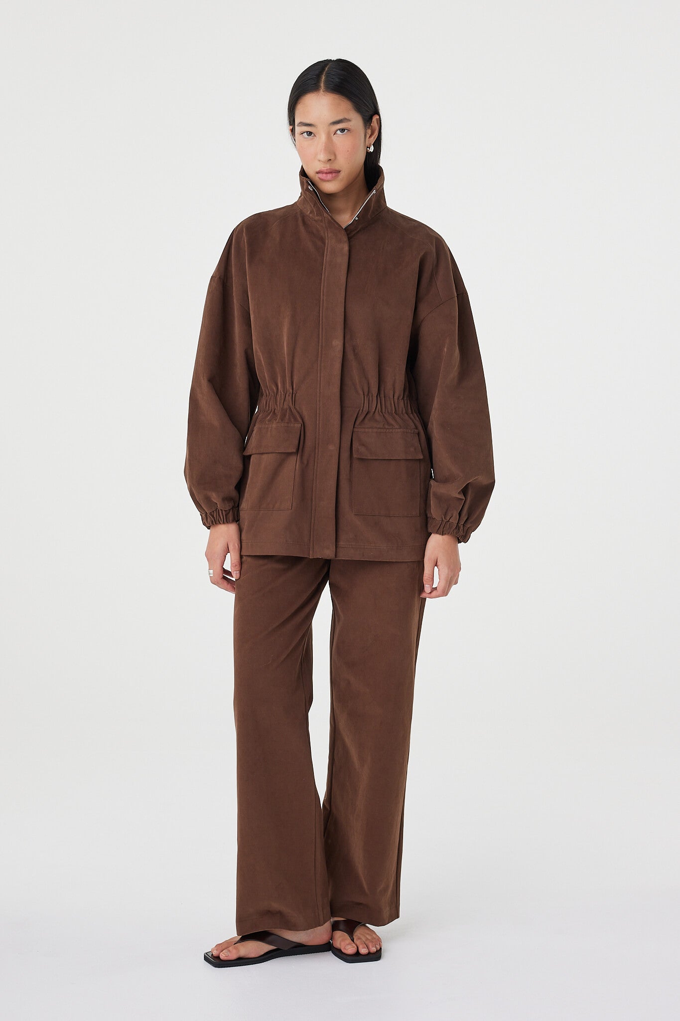 Amari Jacket in espresso styled with matching wide-leg pants and black sandals, featuring oversized front pockets, concealed zip closure and a relaxed silhouette
