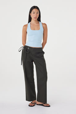 Full-length view of the Sable Top in Pale Blue showcasing the clean fitted shape and smooth finish, paired with charcoal wide-leg wrap trousers and sandals.