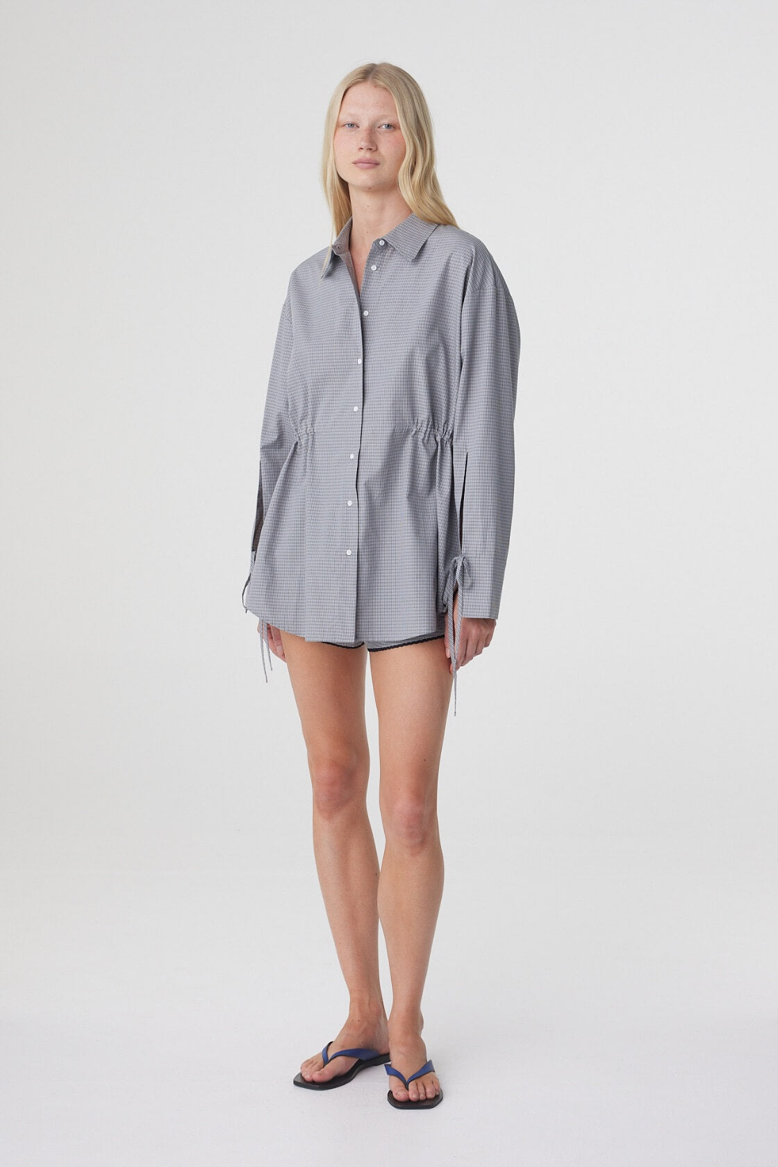 Angled full length view of the Sia Shirt in Muted Blue Check, showing the adjustable waist and relaxed sleeves.