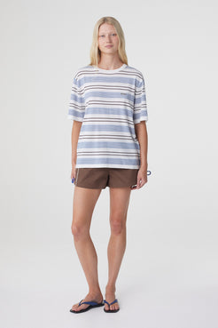 Noor Tee in White & Blue Retro Stripe, full length angled view styled with brown shorts, showing the easy fit and length through the body.