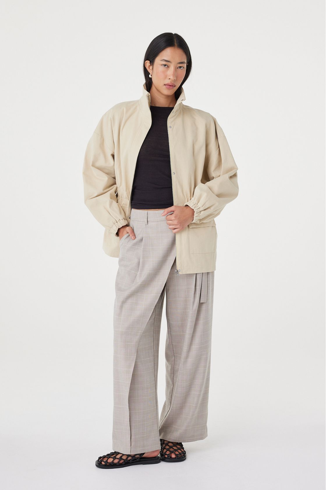 Full-length view of the Amari Jacket in Beige worn open over a dark top, showcasing the lightweight cotton fabrication and relaxed fit.