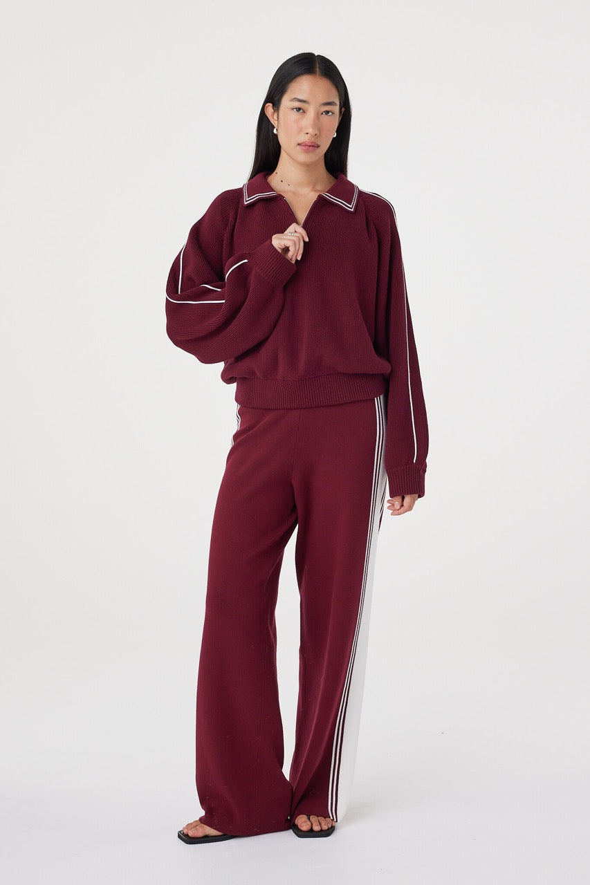 Relaxed front-facing view of the Nella Zip in merlot and cream styled with matching wide-leg knit pants, featuring raglan sleeves, ribbed trims and silver zip neckline detailing