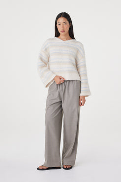 Full-length front view of the Lucca Sweater in taupe and blue stripe styled with wide-leg taupe pants and black sandals, featuring a cropped silhouette and wide sleeve shape
