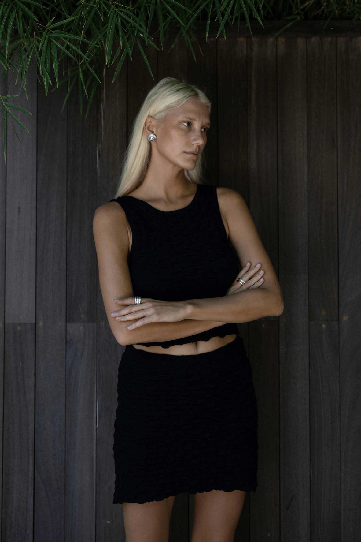 Model wearing the Mila Tank in Black with a matching skirt, showcasing its textured bubble knit and fitted silhouette under soft evening lighting.