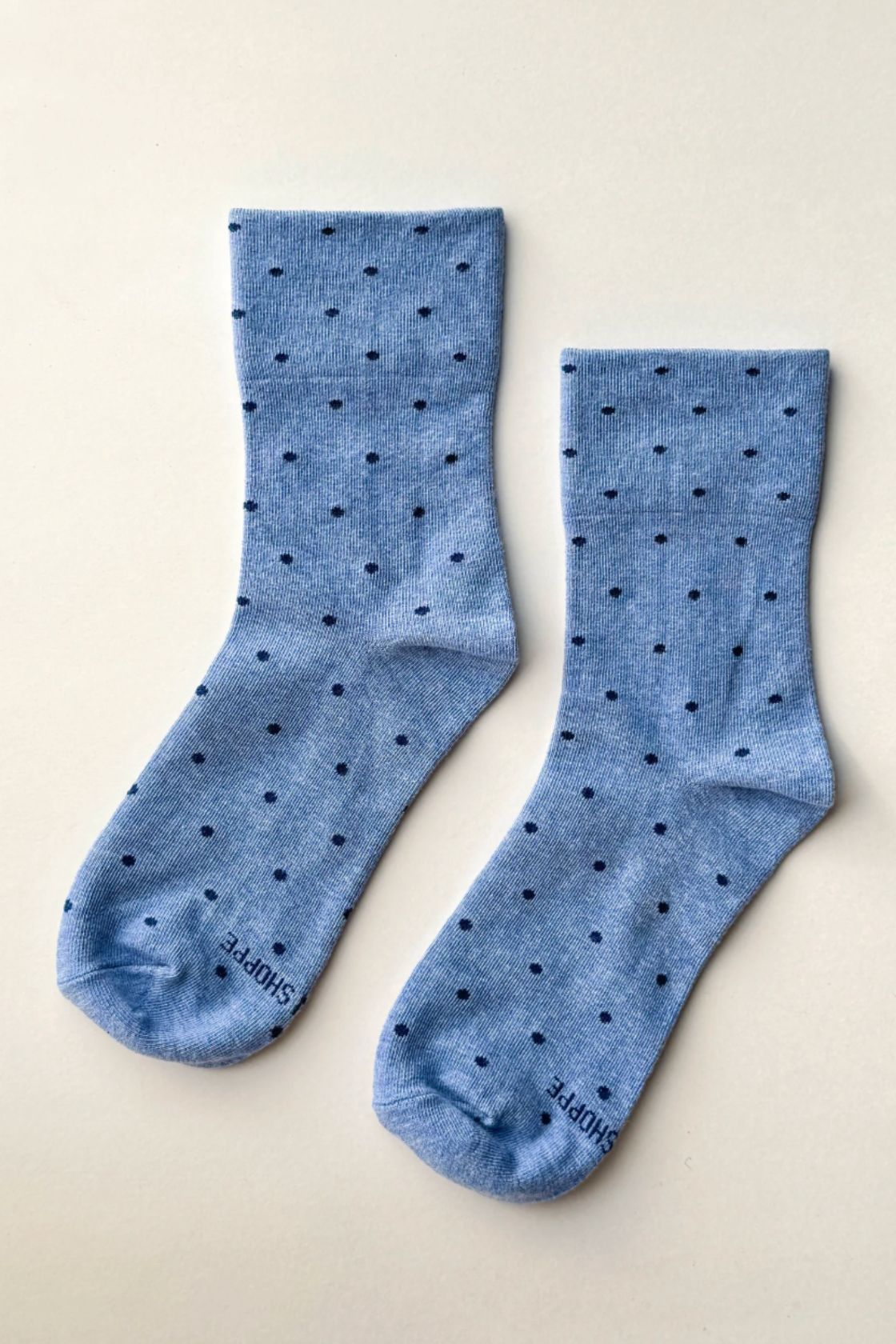 Pair of light blue socks with polka dot detail laid flat showing crew length
