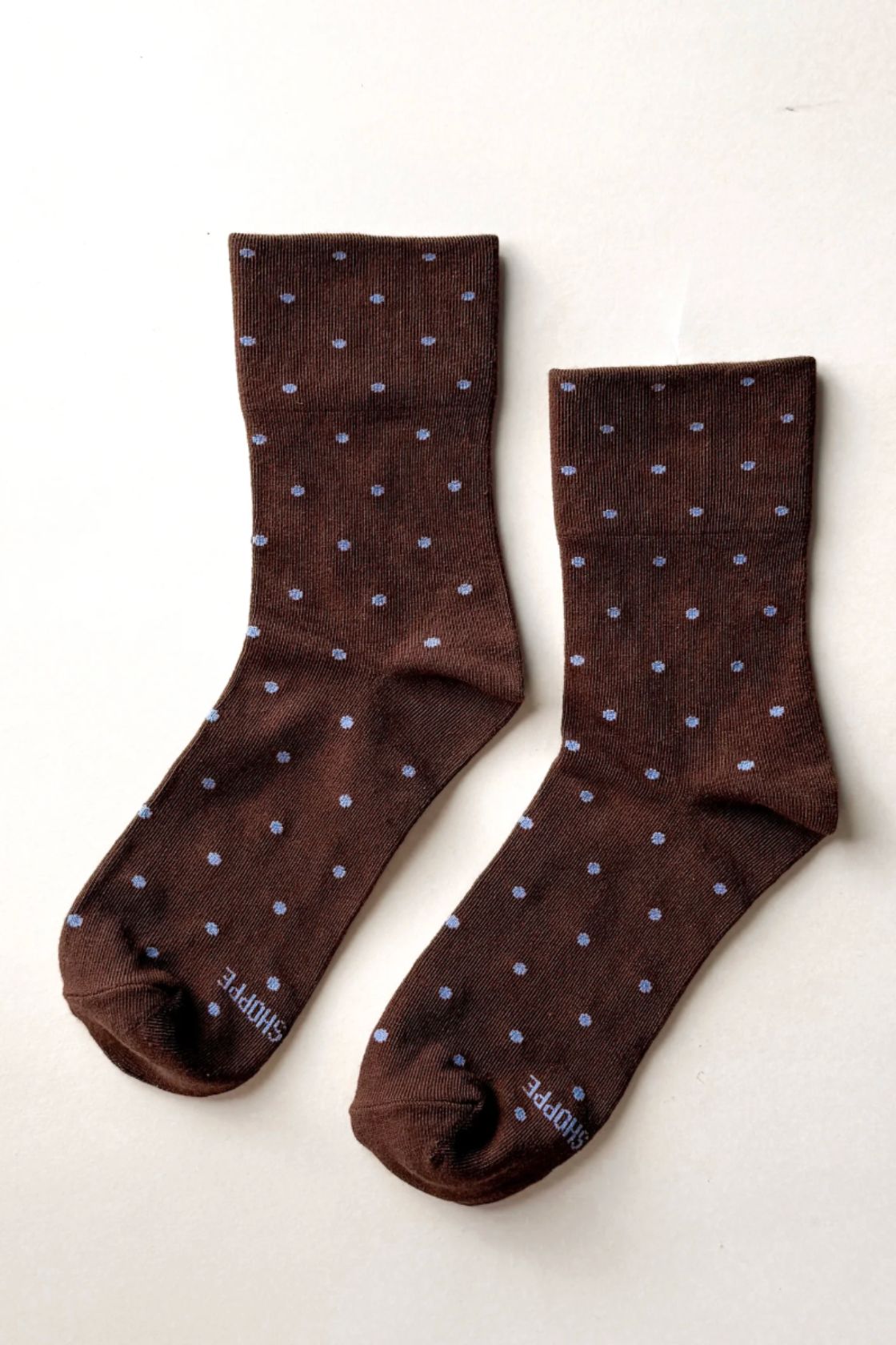 Pair of brown socks with blue dot detail laid flat showing crew length