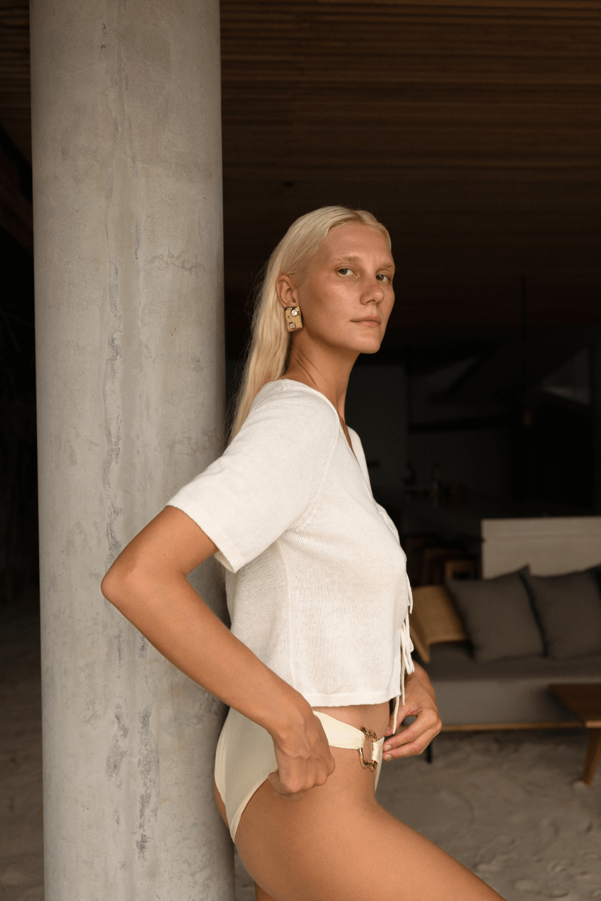 Campaign model wearing the Poppy Short Sleeve Top in Cream, paired with high-cut briefs, showcasing its lightweight linen-cotton fabric and elegant tie detail in soft natural lighting.