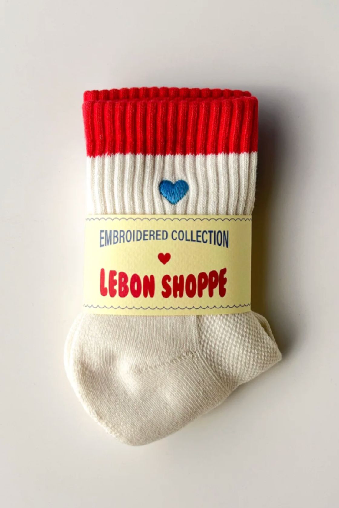 Cream socks with red ribbed cuff and blue heart embroidery, folded with Le Bon Shoppe label