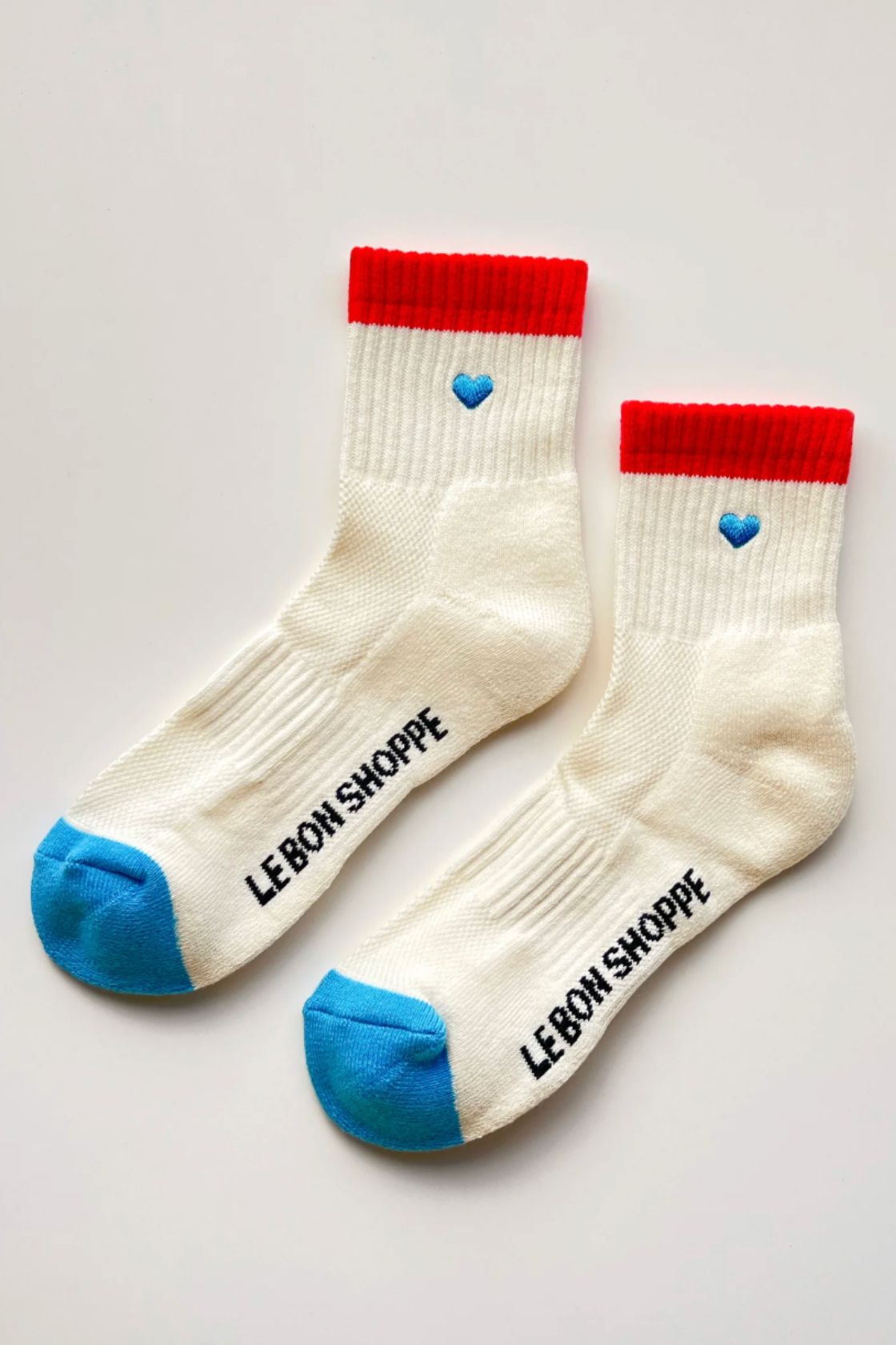 Pair of cream socks with red cuff and blue toe and heel laid flat showing contrast details