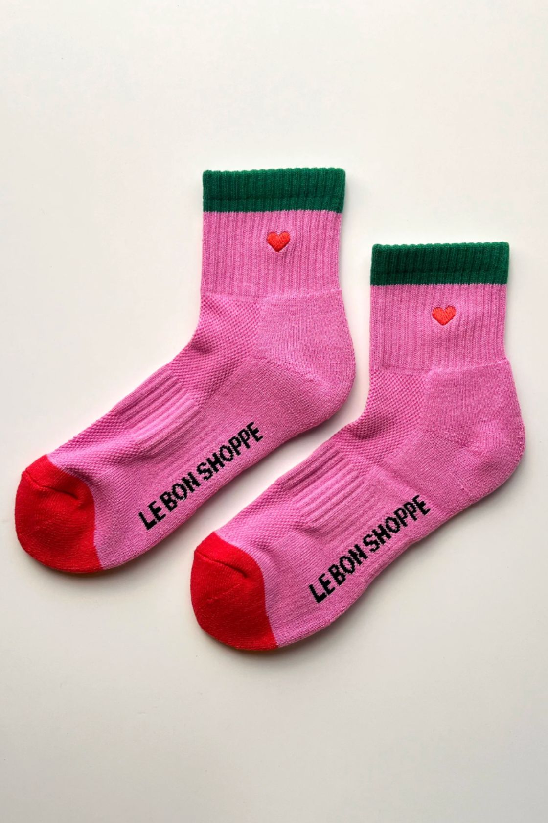 Pair of pink socks with green cuff and red toe and heel laid flat showing contrast details