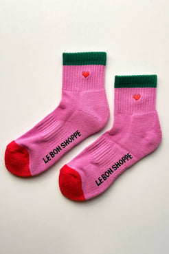 Pair of pink socks with green cuff and red toe and heel laid flat showing contrast details