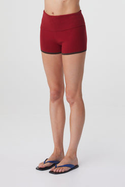 Tove Short in Chilli, close three quarter view highlighting the asymmetric waistband and smooth stretch cotton finish.