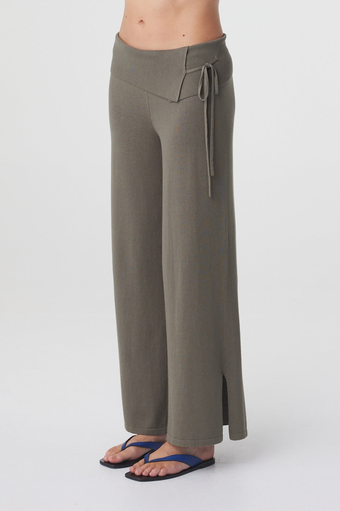Nora Pant in Smokey Olive, angled detail view highlighting the asymmetrical fold over waist, tie detail and split hem.
