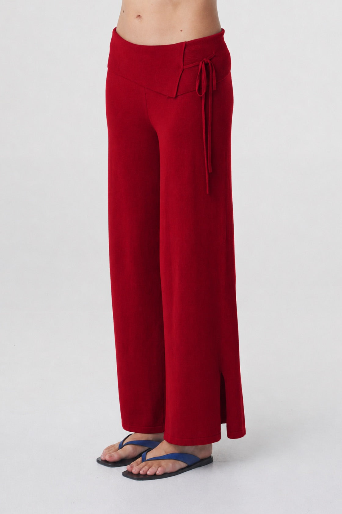 Nora Pant in Chilli, close three quarter view highlighting the asymmetrical waistband, waist tie and side seam split at the hem.