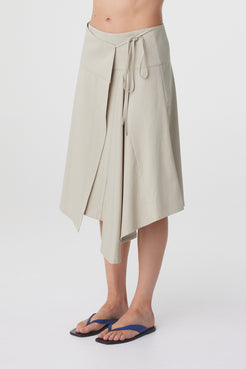 Anya Skirt in Taupe, close three quarter view showing the wrap front, waist tie and layered asymmetric hem.
