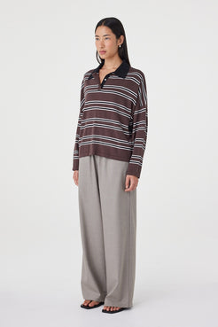 Side profile view of the Rayne Knit in espresso, black and cream paired with wide-leg taupe pants and black sandals, highlighting the drape through the body and dropped shoulder fit
